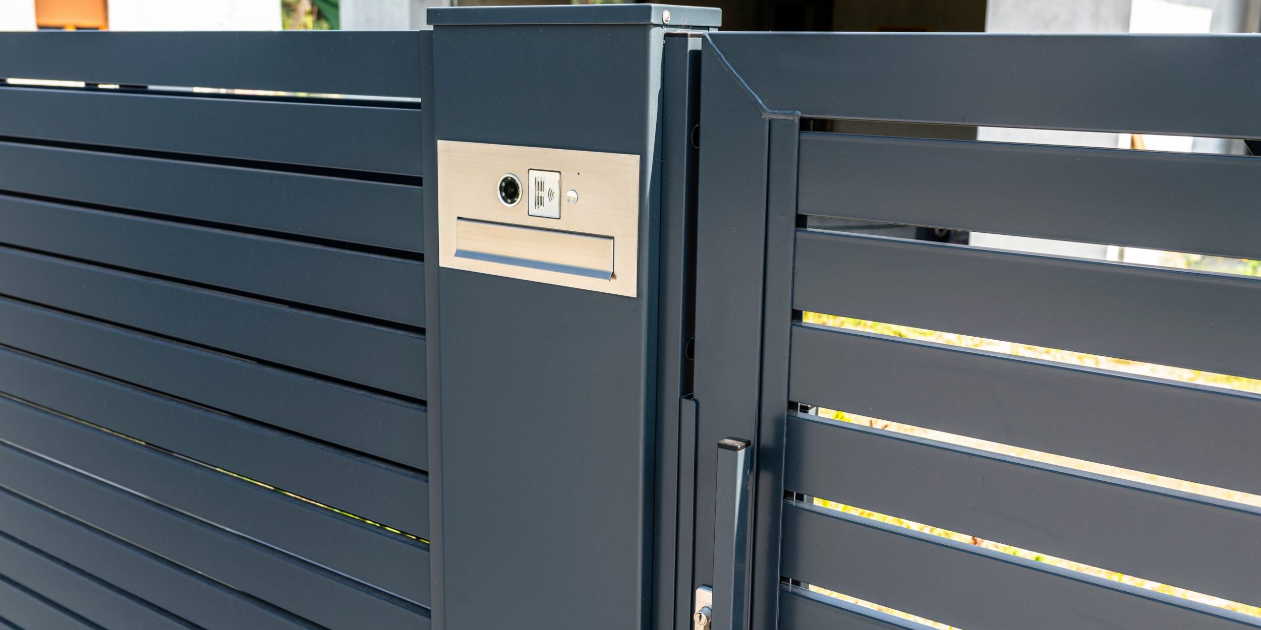 A modern videophone with a letterbox and a wireless card reader, mounted in panel fence in anthracite color, visible wicket.